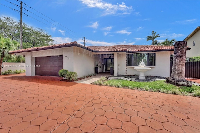 ranch-style house with stucco siding, driveway, an attached garage, a tiled roof, and fence