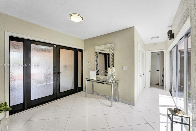 foyer entrance with light tile patterned floors, french doors, and baseboards