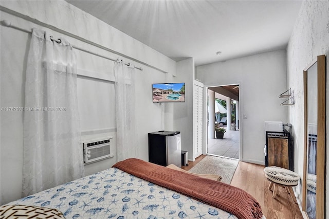 bedroom with a wall mounted air conditioner and wood finished floors