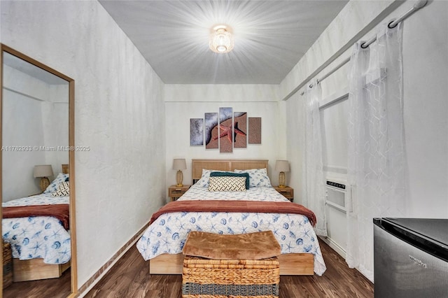 bedroom with baseboards, fridge, and wood finished floors