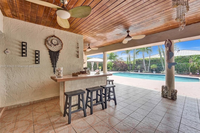 outdoor pool with a patio area, outdoor dry bar, and fence