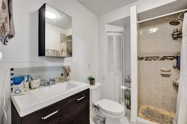 bathroom featuring a closet, toilet, vanity, decorative backsplash, and tiled shower