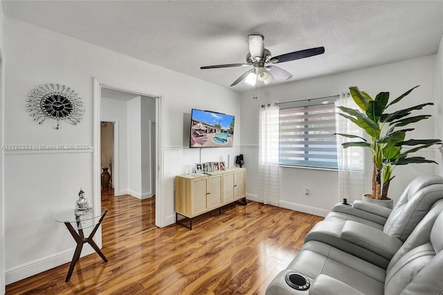 living room featuring light wood-style flooring, ceiling fan, and baseboards