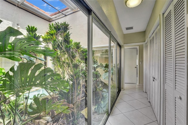 hall featuring visible vents, a skylight, and light tile patterned floors