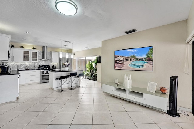 living area featuring a textured ceiling, light tile patterned flooring, and visible vents