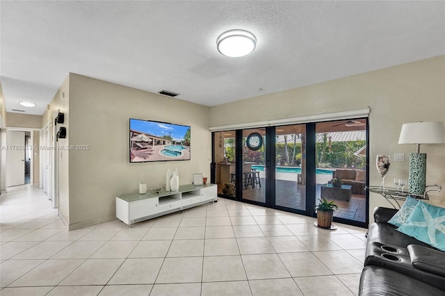 living room with light tile patterned floors, french doors, a textured ceiling, and visible vents