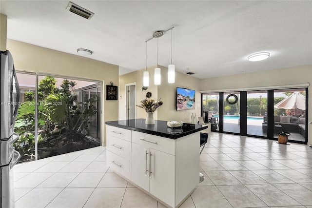 kitchen with visible vents, light tile patterned floors, dark countertops, white cabinetry, and pendant lighting