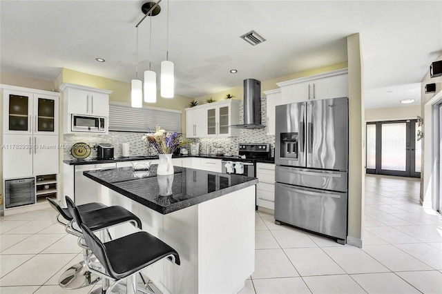 kitchen with visible vents, wall chimney range hood, dark countertops, appliances with stainless steel finishes, and backsplash