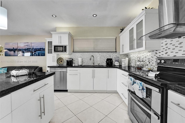 kitchen with a sink, backsplash, appliances with stainless steel finishes, and wall chimney exhaust hood
