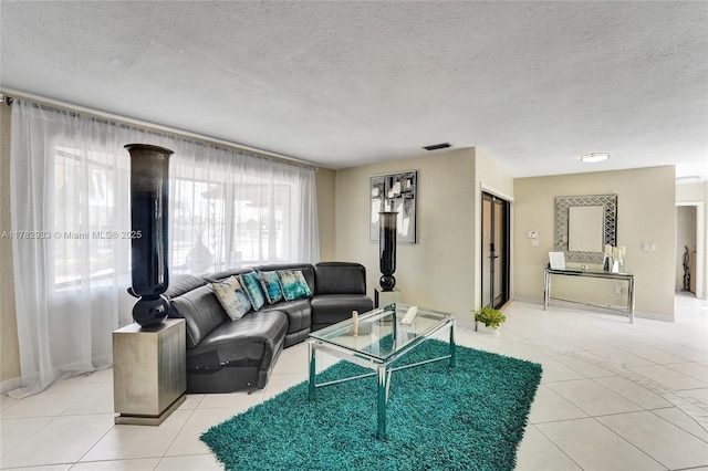 living area with a textured ceiling, light tile patterned floors, baseboards, and visible vents