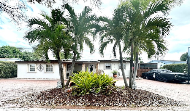 single story home with roof mounted solar panels, driveway, and stucco siding