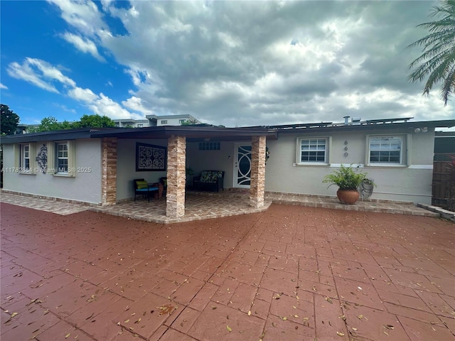 back of property with a patio and stucco siding