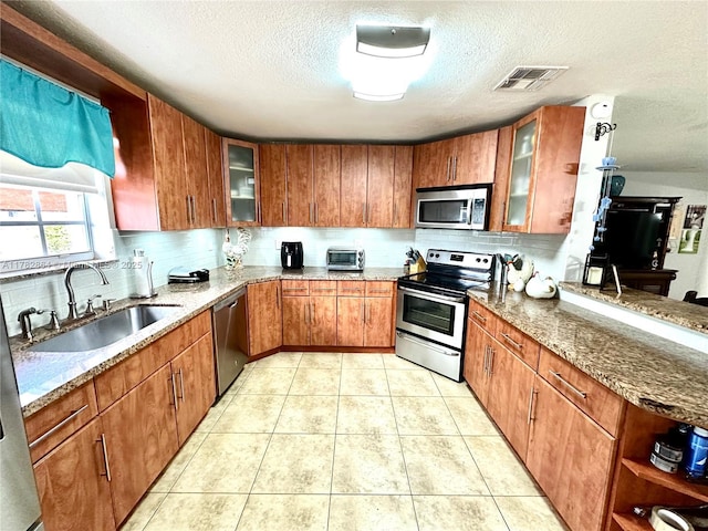 kitchen featuring a textured ceiling, light stone countertops, visible vents, appliances with stainless steel finishes, and a sink