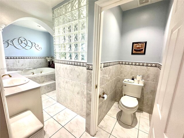 full bathroom featuring tile patterned flooring, toilet, a bath, tile walls, and a sink