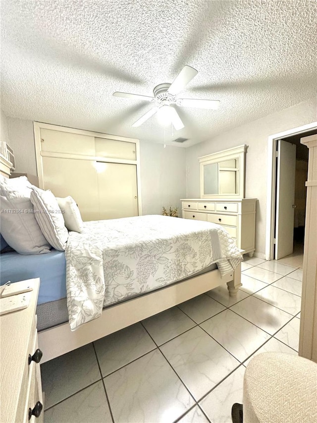 bedroom featuring visible vents, a ceiling fan, light tile patterned flooring, and a textured ceiling