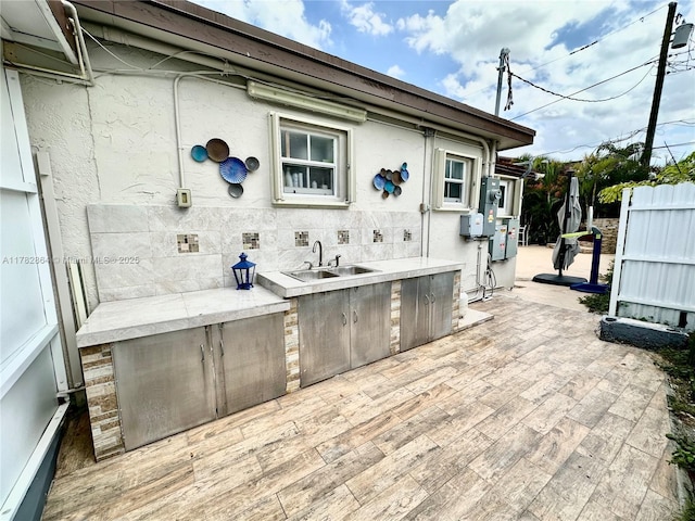 view of patio / terrace featuring a sink, fence, and exterior kitchen