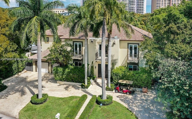 31 Island Dr, Key Biscayne, FL 33149 - view of front facade with a tile roof, stucco siding, a balcony, decorative driveway, and french doors