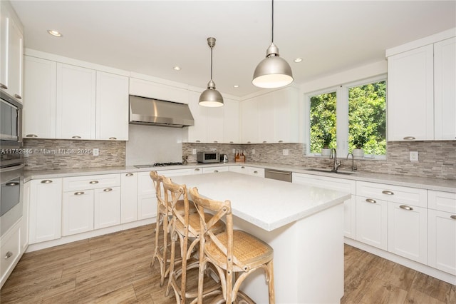 31 Island Dr, Key Biscayne, FL 33149 - kitchen with wall chimney range hood, a sink, light wood finished floors, appliances with stainless steel finishes, and recessed lighting