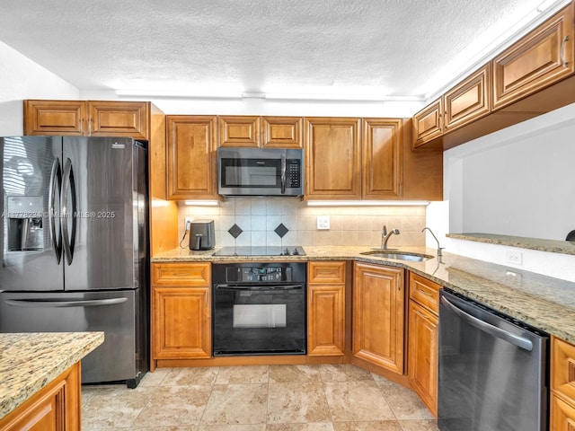 kitchen featuring a textured ceiling, light stone counters, a sink, and black appliances