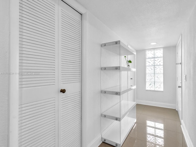 interior space with a closet, tile patterned floors, a textured ceiling, and baseboards
