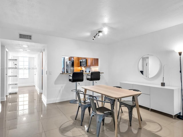 dining space with light tile patterned floors, visible vents, and baseboards
