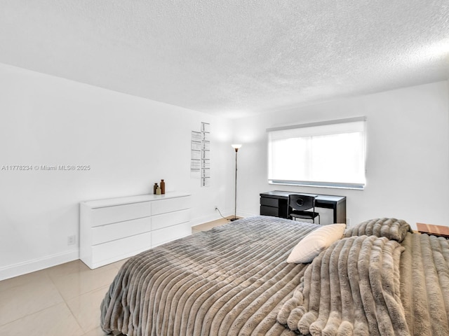 bedroom with tile patterned flooring, baseboards, and a textured ceiling