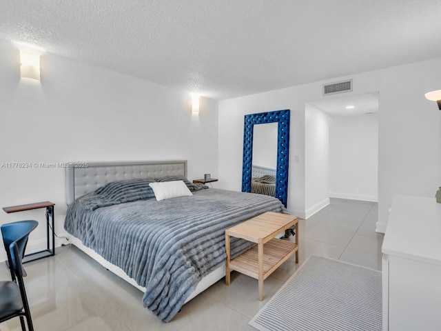 bedroom with visible vents, tile patterned floors, baseboards, and a textured ceiling