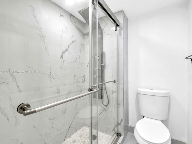 bathroom featuring toilet and a marble finish shower