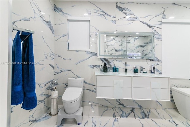 bathroom with toilet, marble finish floor, vanity, and tile walls