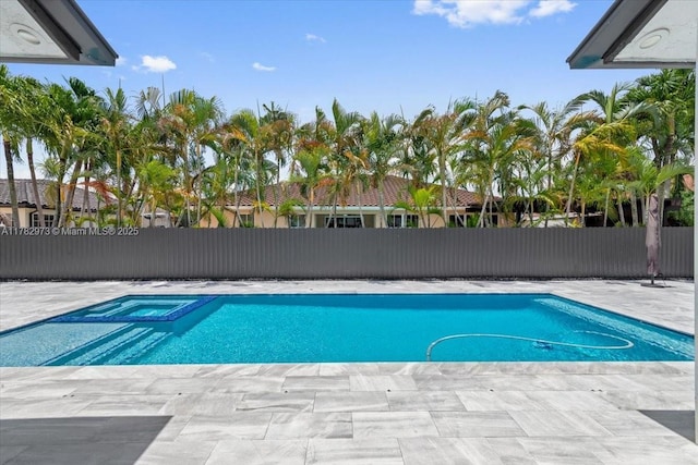 view of swimming pool featuring a patio area, a pool with connected hot tub, and fence