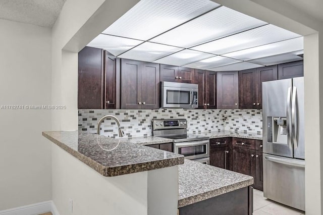 9050 NW 28th St Unit 114, Coral Springs, FL 33065 - kitchen with appliances with stainless steel finishes, a peninsula, dark brown cabinets, and decorative backsplash
