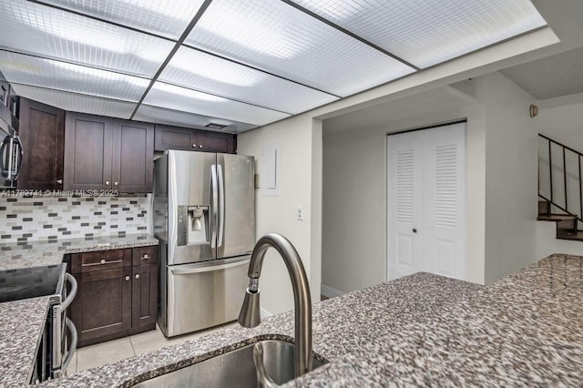 9050 NW 28th St Unit 114, Coral Springs, FL 33065 - kitchen with stainless steel appliances, tasteful backsplash, dark brown cabinetry, dark stone counters, and light tile patterned flooring