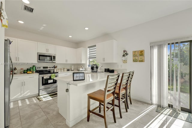20900 NE 2nd Ct, Miami, FL 33179 - kitchen with a healthy amount of sunlight, visible vents, a breakfast bar, and appliances with stainless steel finishes