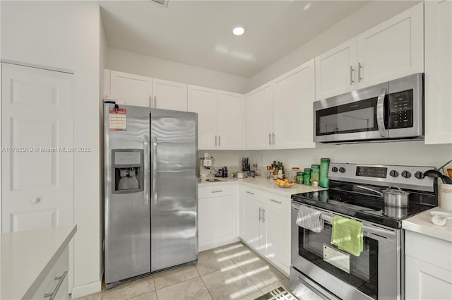20900 NE 2nd Ct, Miami, FL 33179 - kitchen with light tile patterned floors, light countertops, white cabinets, and stainless steel appliances
