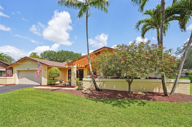 view of front of property featuring a front yard, driveway, stucco siding, and an attached garage