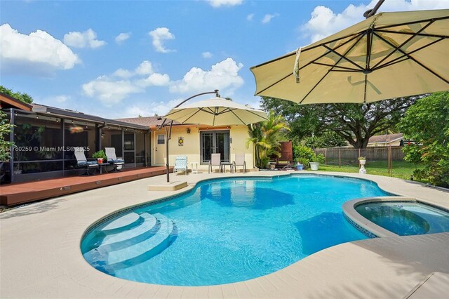 view of pool with a wooden deck, a pool with connected hot tub, a patio area, fence, and french doors
