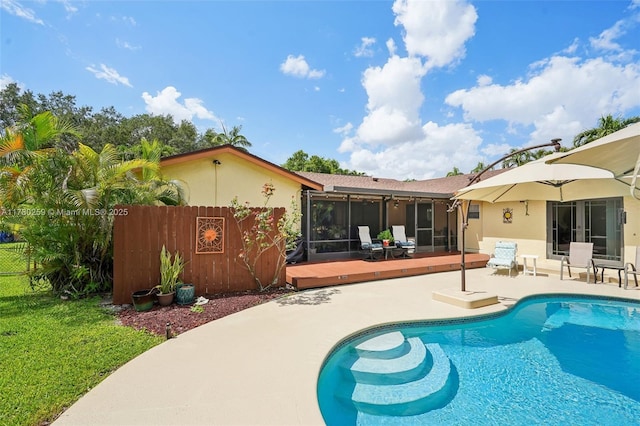back of house with a sunroom, fence, stucco siding, a wooden deck, and a fenced in pool