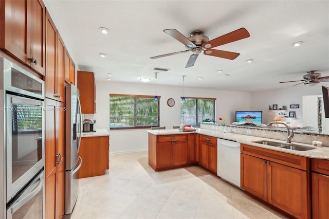 kitchen with brown cabinetry, appliances with stainless steel finishes, ceiling fan, and a sink