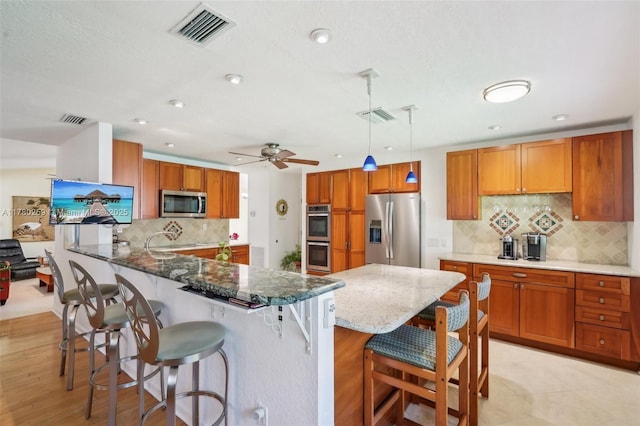 kitchen featuring tasteful backsplash, appliances with stainless steel finishes, and visible vents