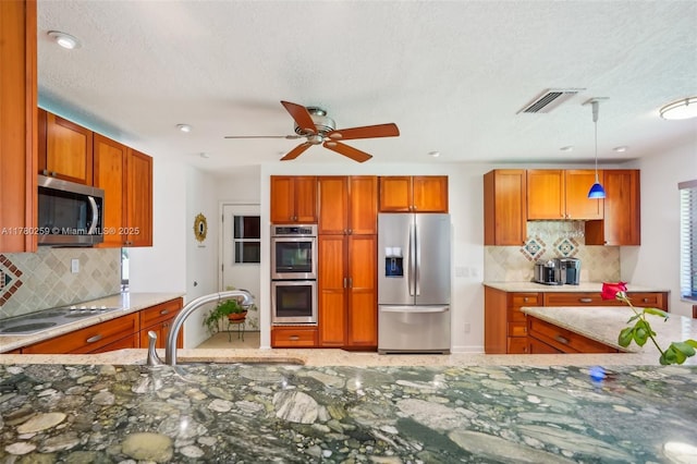 kitchen with a sink, brown cabinetry, appliances with stainless steel finishes, and decorative backsplash