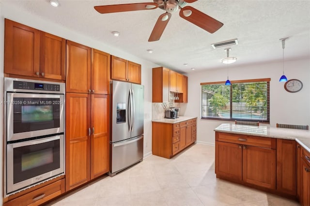 kitchen with a ceiling fan, visible vents, brown cabinetry, stainless steel appliances, and pendant lighting