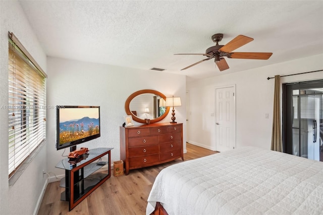 bedroom with baseboards, visible vents, light wood-type flooring, and a textured ceiling