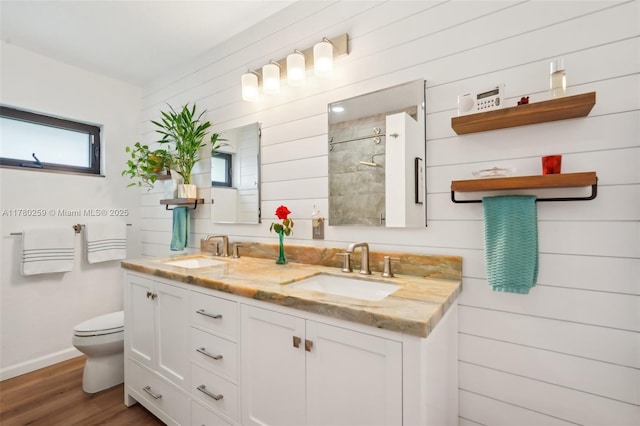 full bathroom with double vanity, baseboards, a sink, and wood finished floors