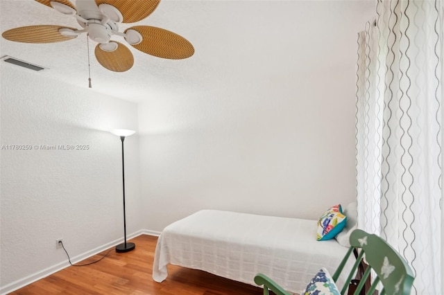 bedroom featuring light wood finished floors, visible vents, baseboards, and a ceiling fan