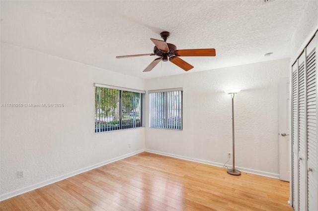unfurnished bedroom featuring a closet, light wood-style floors, baseboards, and ceiling fan