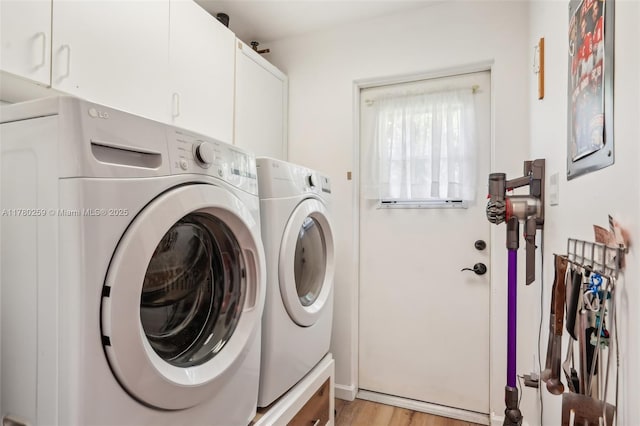 washroom with light wood-style flooring, cabinet space, and washing machine and dryer