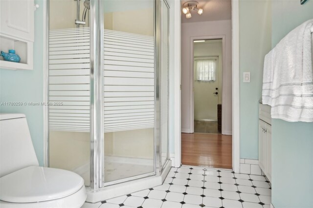 bathroom with toilet, tile patterned floors, and a stall shower