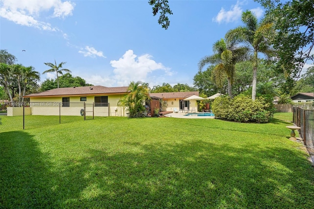 back of property with a fenced backyard, a fenced in pool, a lawn, and stucco siding