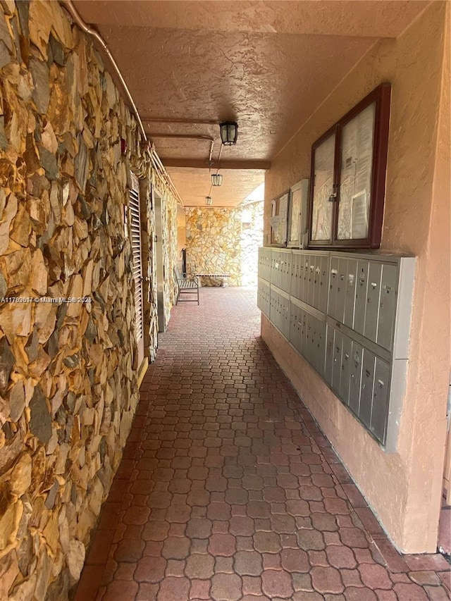 hall featuring a textured wall and mail area