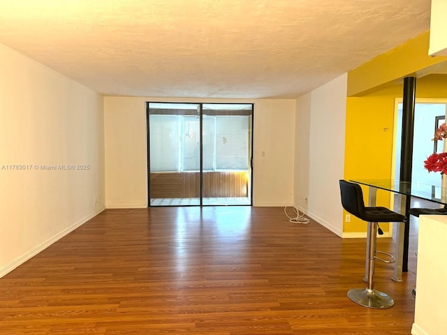 spare room featuring a textured ceiling, wood finished floors, baseboards, and a wall of windows